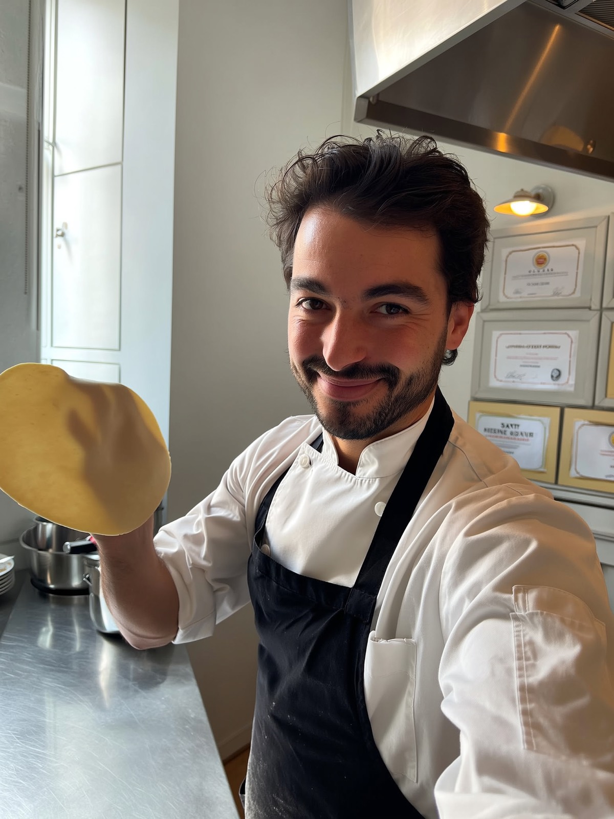 A chef in his kitchen, mid-prep, holding up fresh pasta dough
