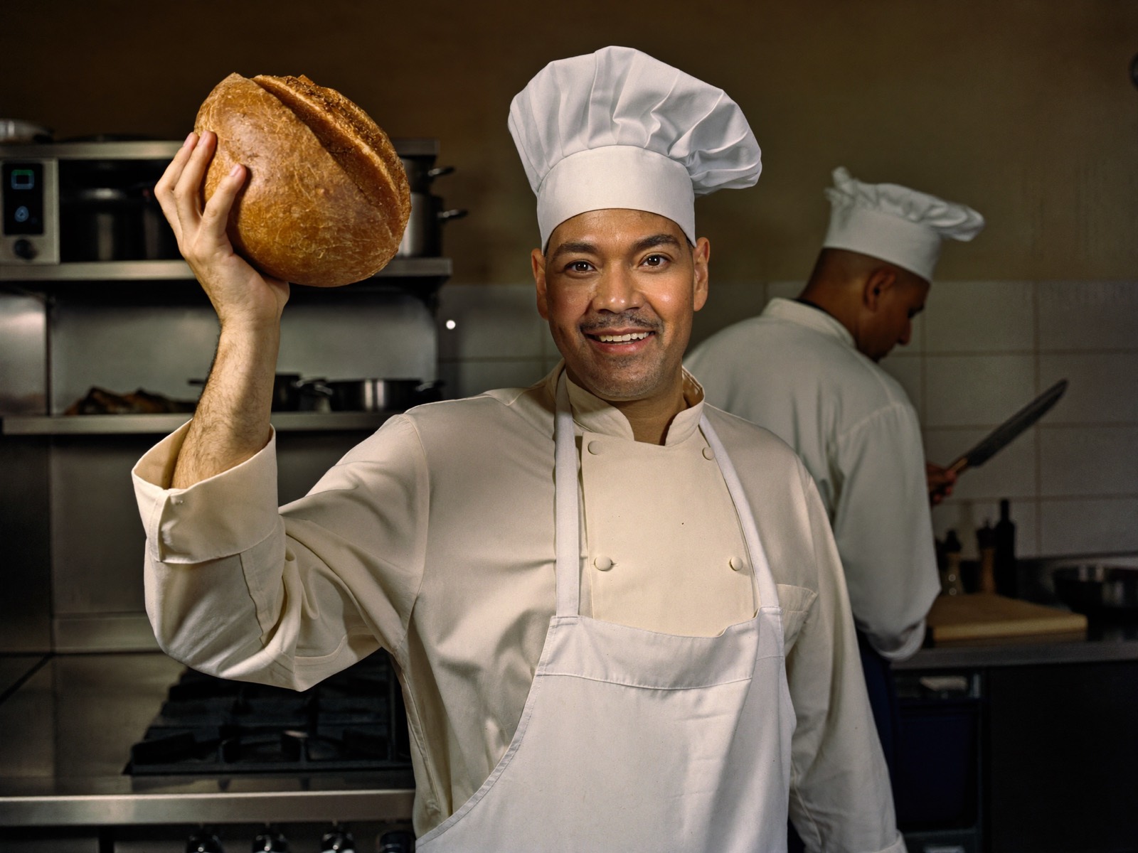 A baker holding up a fresh loaf